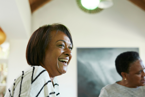 Close-up of cheerful mature woman looking away while sitting with female friend at home in Christmas party