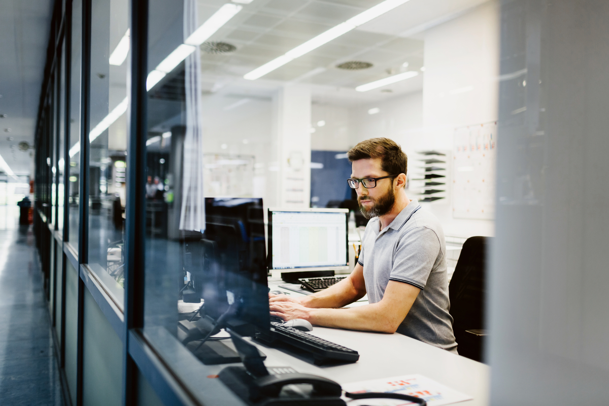 Man sitting inside of an office working on a computer.