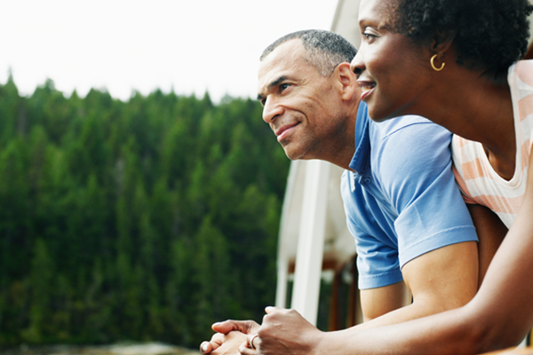 Couple standing next to each other outside. Trees in background